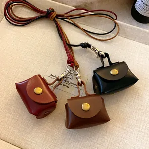 Detailed view of three mini leather pouch necklaces in red, brown, and black tones