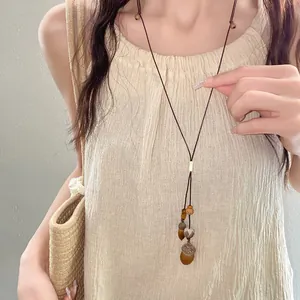 Primo piano di una collana in stile etnico con perle in legno e ciondoli a ghianda
