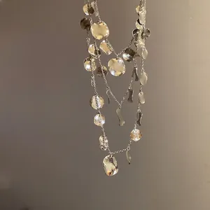 Close-up of a triple-layered silver necklace featuring irregular hammered disc charms.