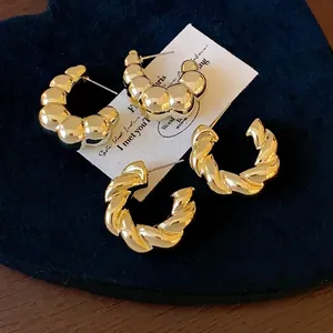 Elegantes pendientes de aro en forma de C dorados retorcidos y con textura de burbuja.
