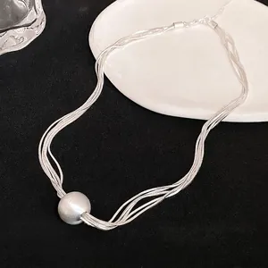 Elegant multi-strand silver necklace featuring a large metallic ball pendant detail