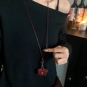 Detailed view of leather mini earphone pouch necklace worn on a black sweater