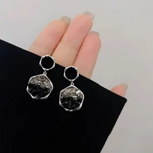 Detailed view of silver-tone geometric earrings accented with black and clear crystal stones.