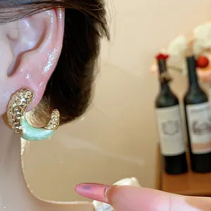 Close-up of light green enamel C-shaped hoop earring with gold wrinkled texture