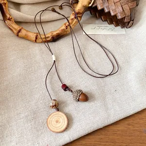 Primo piano di una collana retrò con ciondolo a ghianda e legno su tessuto