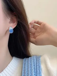 Detail showing elegant blue and white crystal geometric stud earring worn by model on ear