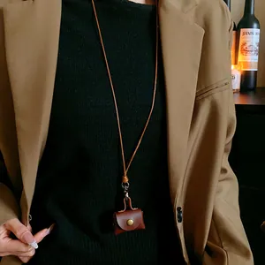 Detailed view of a vintage brown leather mini pouch necklace worn on a stylish black top