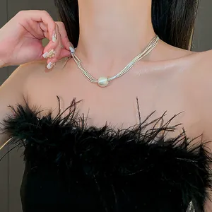 Detail of multi-strand silver necklace featuring a large central pearl pendant.