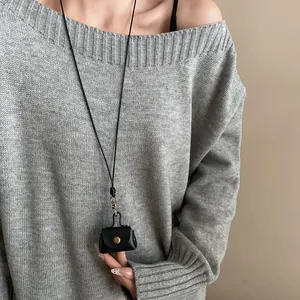 Close-up of a vintage black leather mini bag necklace worn over a grey knit sweater.