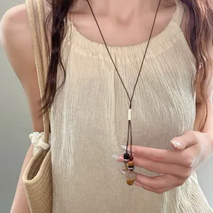 Vista dettagliata di una collana etnica con corda cerata e perline di legno su un modello.