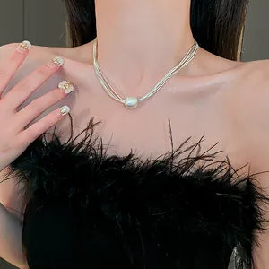 Detail of a stylish multi-layer silver necklace with a large white pearl on model