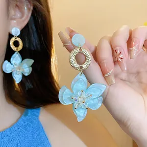 Detail of light blue resin flower earrings with gold ring and silver needle