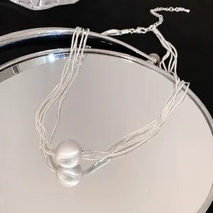 Close-up of silver multi-layer necklace featuring a minimalist round ball pendant