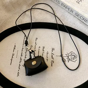 Vintage black leather mini pouch necklace for earphones and coins, displayed on a decorative tray