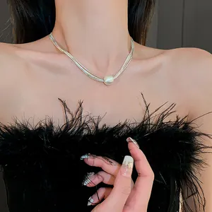 Close-up of elegant multi-strand silver necklace with central pearl on model