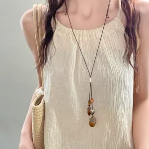 Collana etnica vintage con perle di legno e ciondoli a forma di ghianda e cachi su corda.