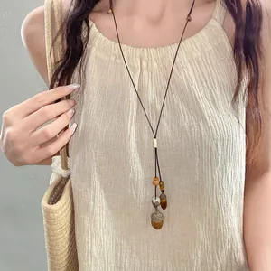 Dettaglio collana fatta a mano con ciondolo ghianda e cachi su modella stile naturale