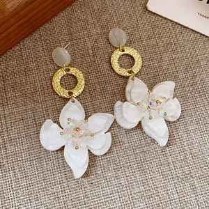 Detail of resin flower drop earrings with golden textured ring and iridescent bead centers