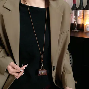 Detailed view of a vintage brown leather mini coin pouch necklace worn by a model in a blazer