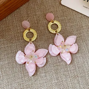 Detailed close-up view of elegant pink resin flower earrings with gold textured rings.