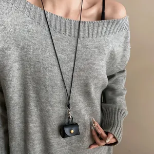 Close-up of a vintage black leather pouch necklace worn over a gray knit sweater