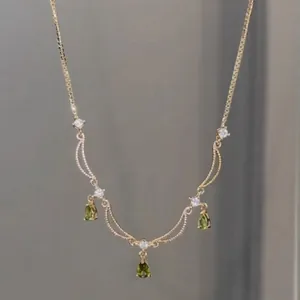 Collier élégant plaqué or 18 carats avec pendentifs gouttes vertes et zircons étincelants.