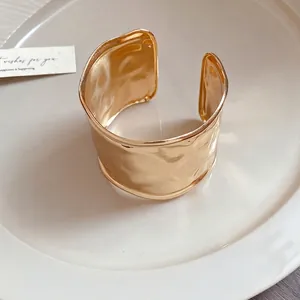 Eleganter minimalistischer breiter goldener Armreif mit Hammerschlag-Struktur-Finish