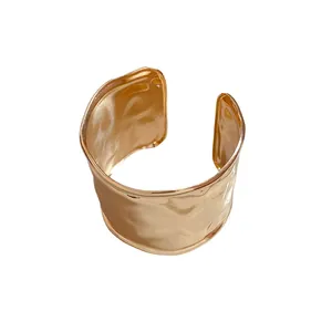 Minimalistischer breiter goldener Metall-Armreif mit unregelmäßiger Hammerschlag-Textur