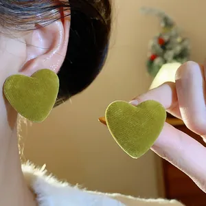 Detailed close-up of olive green velvet heart earrings with soft flocking texture.