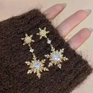 Macro detail of gold-plated snowflake drop earrings inlaid with sparkling zircon.
