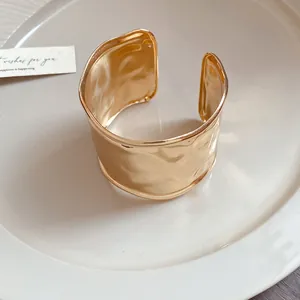 Detaillierte Nahaufnahme eines breiten goldenen Armreifs mit gehämmerter Textur-Stil
