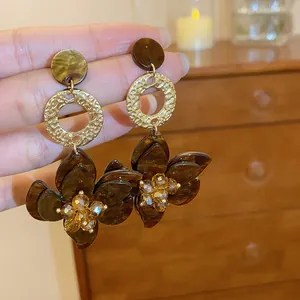 Detailed view of amber resin flower earrings with gold textured rings and crystals