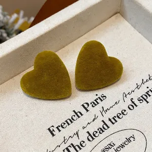 Detail macro view of velvet flocked heart stud earrings in olive green on a vintage card