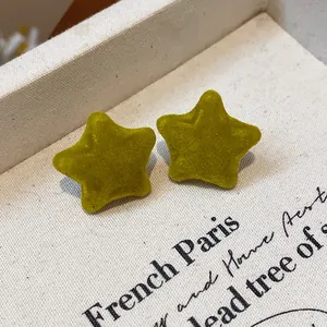 Close-up of yellow star-shaped flocked stud earrings with velvet texture