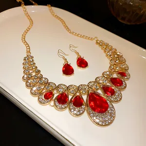 Detailed view of an elegant waterdrop red rhinestone necklace and earring set in gold