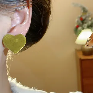Detailed close-up view of a chic green flocked heart stud earring worn by a model