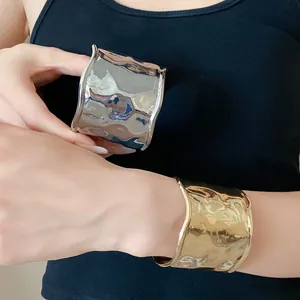 Detailansicht von breiten Metallmanschetten-Armbändern mit wellenförmigem Design.