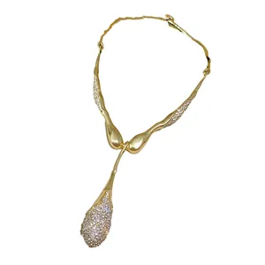 Élégant collier doré avec pendentif goutte d'eau irrégulier et strass brillants.