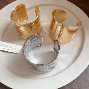 Detailansicht breiter Metallmanschettenarmbänder in gehämmerter Gold- und Silberoptik