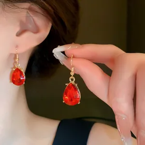 Close-up of elegant red teardrop earrings with faceted gemstones and gold hooks.