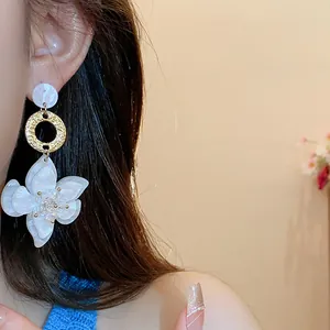 Detailed macro view showing vintage white resin flower dangle earrings worn on an ear