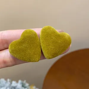 Close-up of mustard yellow heart-shaped earrings with soft flocking velvet texture.
