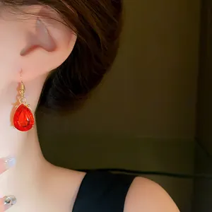Close-up of elegant gold-plated drop earrings featuring faceted red teardrop crystals