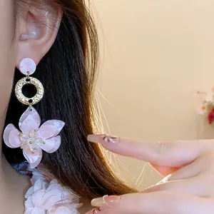 Detailed view of elegant pink resin flower drop earrings with gold textured accents