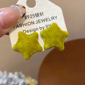 Macro view showing the soft flocked texture of the green star-shaped earrings.