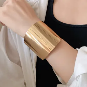 Nahaufnahme eines breiten goldenen Metallarmreifs mit glänzendem Spiegelfinish