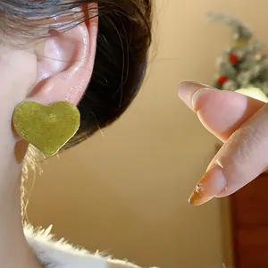 Detailed close-up view of a green flocked heart-shaped stud earring worn on the ear.