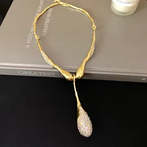 Détail d'un collier doré irrégulier avec pendentif goutte d'eau en strass