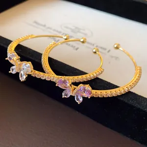 Vue détaillée des breloques papillon en zircon sur des bracelets dorés ouverts