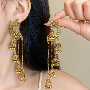 Close-up of gold vintage palace style long tassel earrings with multiple bells worn by a model